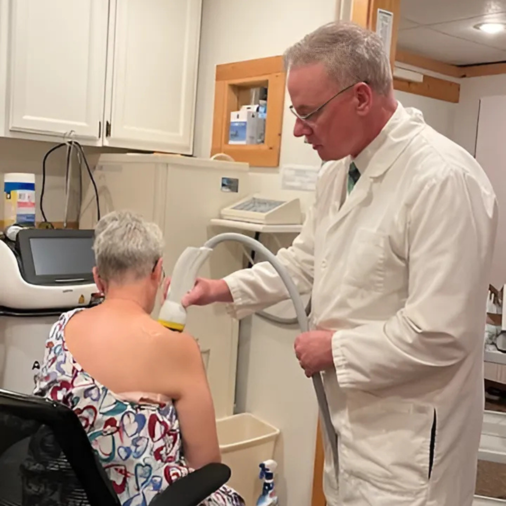 Doctor using softwave therapy on a patient.