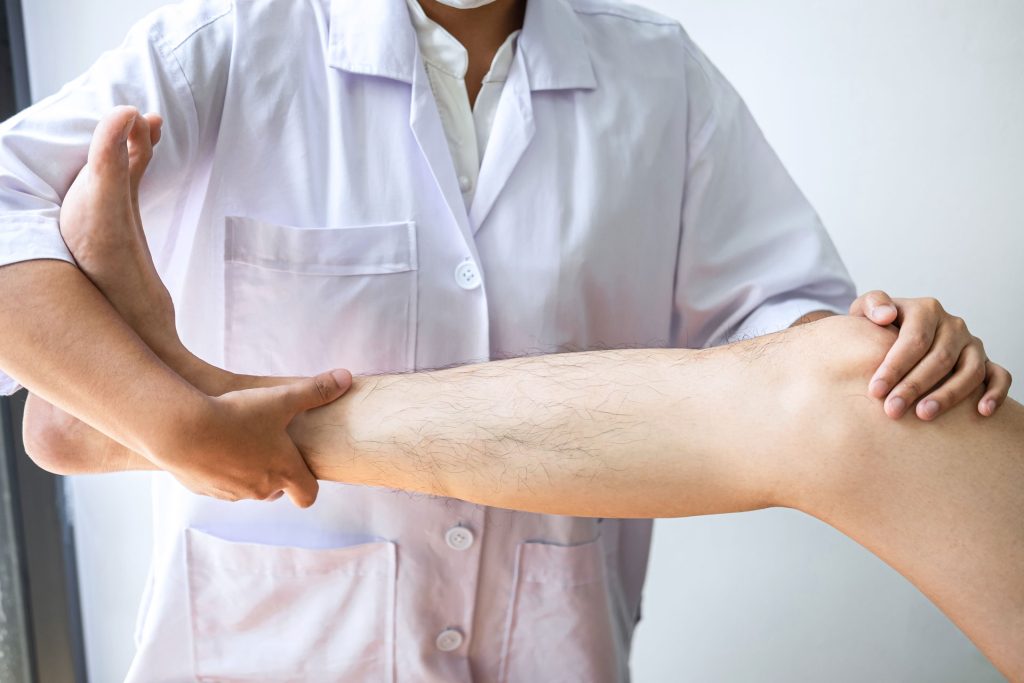 Doctor examining legs of a patient.