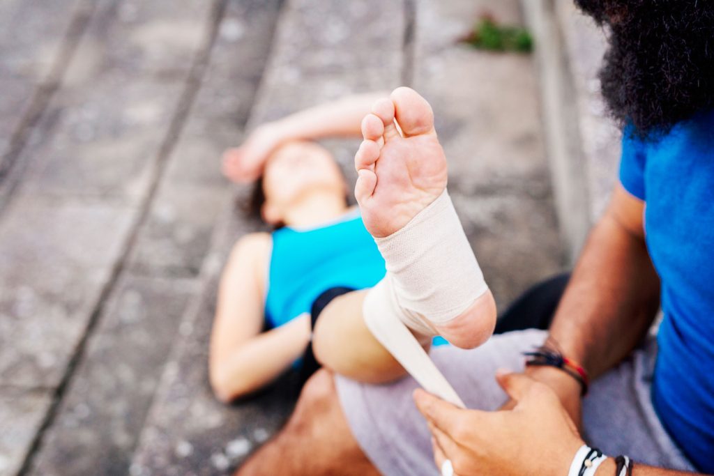 Man wrapping a woman feet with bandages after an injury.