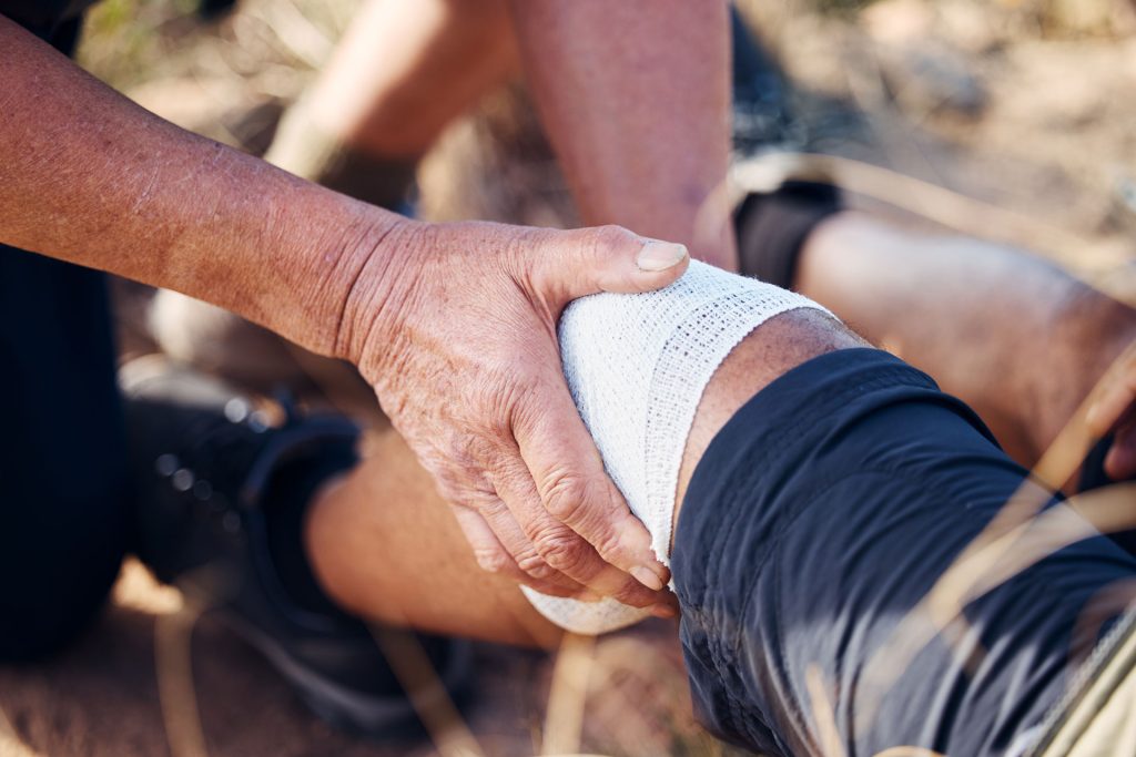 Applying bandages at the knee of injured person.