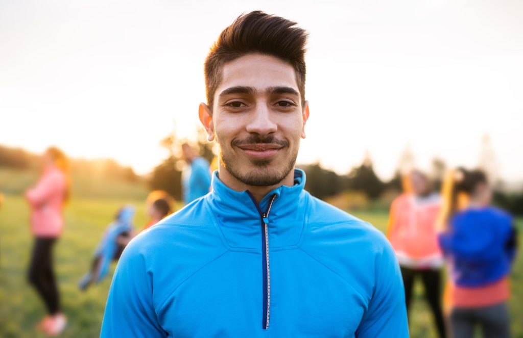 Young fit man in a group of healthy people outdoor.