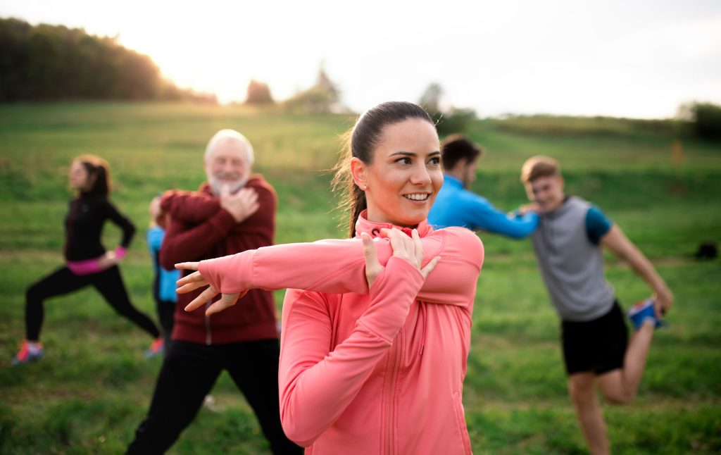 Group of active people stretching outdoors.