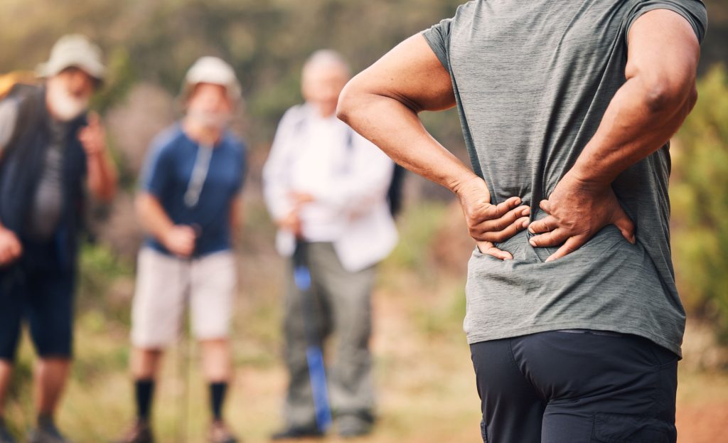 Man with backpain during hiking with friends.