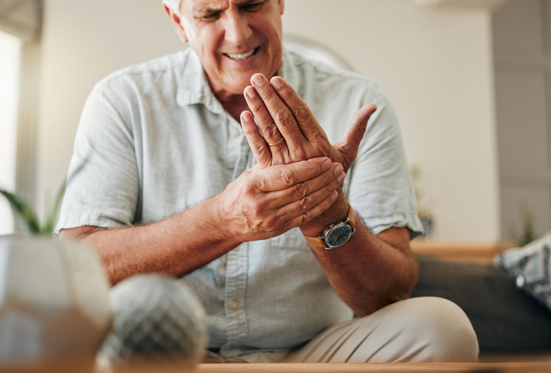 Senior man with arthritis pain in living room.